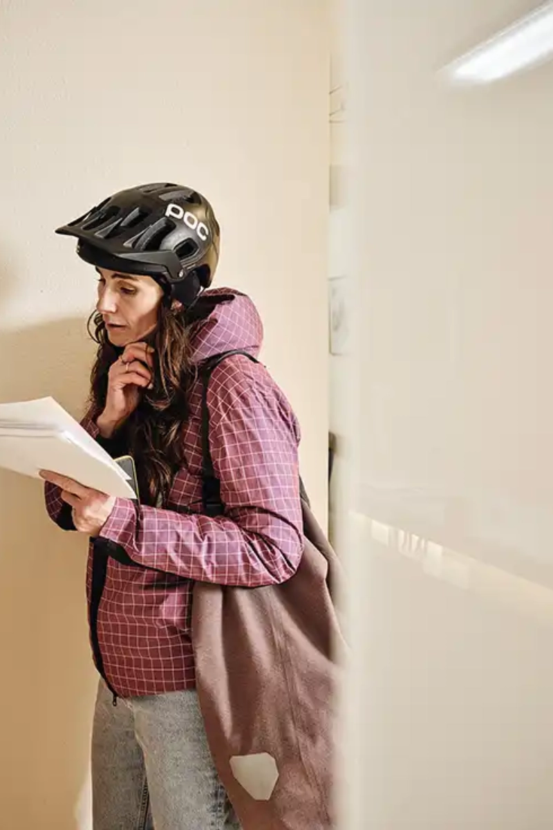 Eine Frau mit Fahrradhelm ist gerade im Büro angekommen und öffnet Post