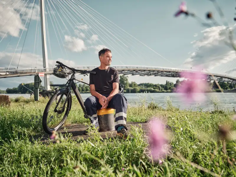 JobRadler Arbeitskleidung sitzt Wiese Brücke