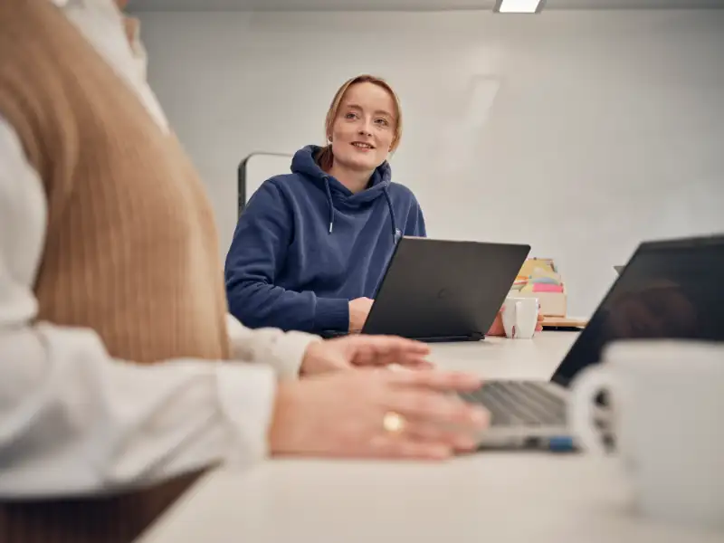 Blonde Frau blickt vom Laptop hoch