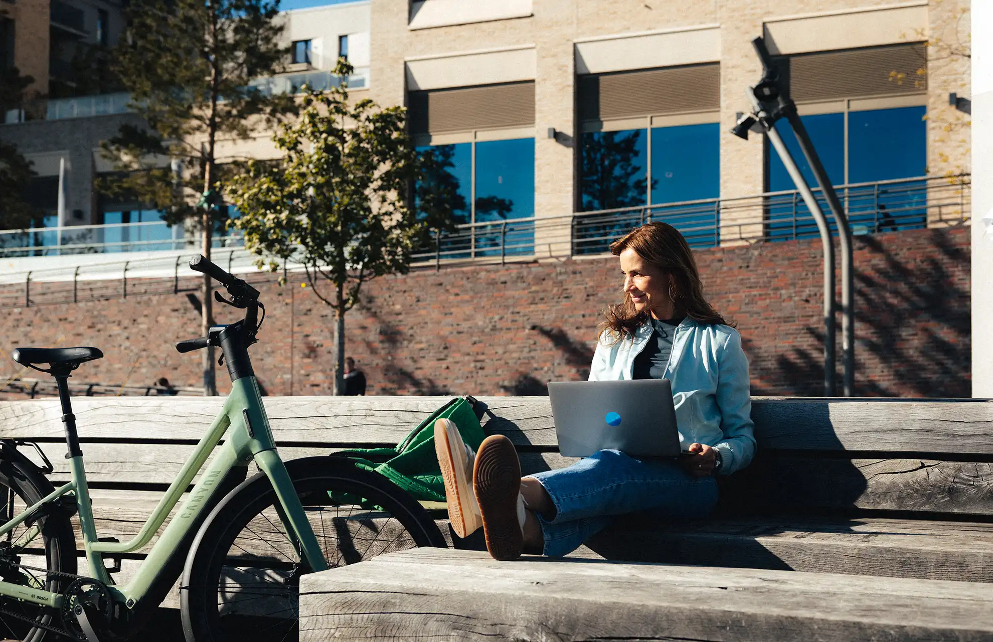 Junge Frau mit-Laptop neben ihrem Dienstradvon JobRad